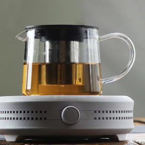 Einfache Teekanne aus Glas mit Aufgussvorrichtung auf einem elektrischen Stövchen.