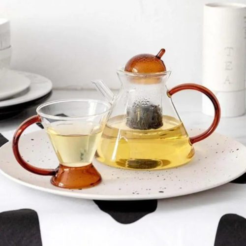 Teekanne aus Glas mit elegantem Design und braunem Griff.