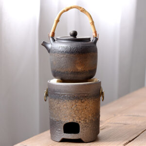 Vintage-stil Große chinesische Teekanne mit Stövchen aus Keramik mit Bambusgriff auf einem Holzuntergrund.