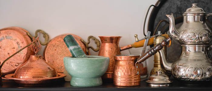 turk-teekanne Traditionelle türkische Teekanne mit verziertem Design, umgeben von Kupfergeschirr und Mörser.